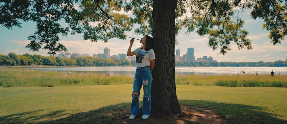 Adults relaxing on an Atlanta rooftop at sunset, enjoying cannabis products with Midtown skyline in background